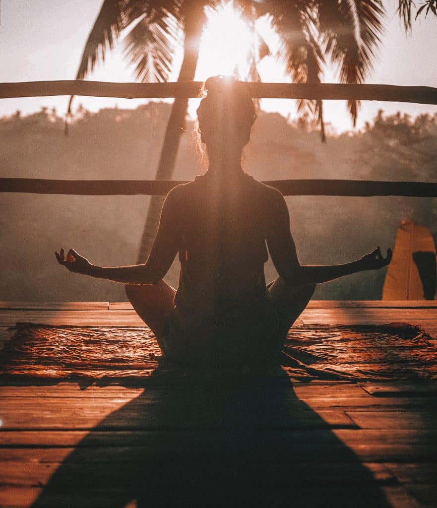 woman sitting in sun doing yoga